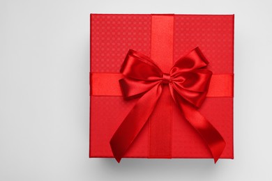 Gift box with bow on light grey background, top view