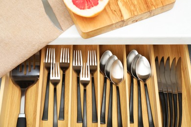 Photo of Box with cutlery in drawer, above view. Kitchen utensils storage