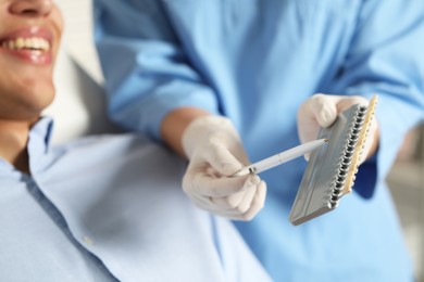 Doctor and patient choosing shade on teeth color palette in clinic, closeup. Dental veneers