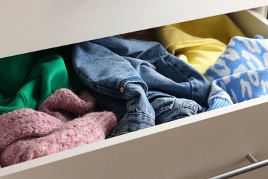 Cluttered chest of drawers indoors, closeup. Clothes in mess