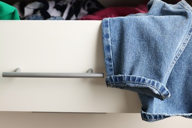 Photo of Cluttered chest of drawers indoors, closeup. Clothes in mess