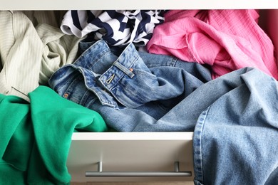 Photo of Cluttered chest of drawers indoors, above view. Clothes in mess