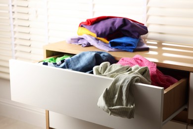 Cluttered chest of drawers indoors, closeup. Clothes in mess