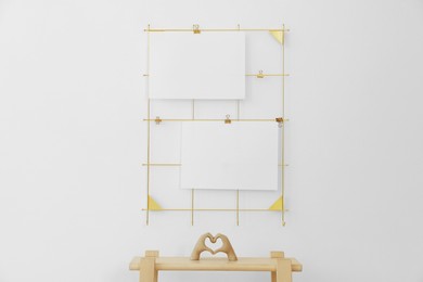 Photo of Mood board with blank paper notes and decorative figure in shape of hands making heart on wooden ladder near white wall