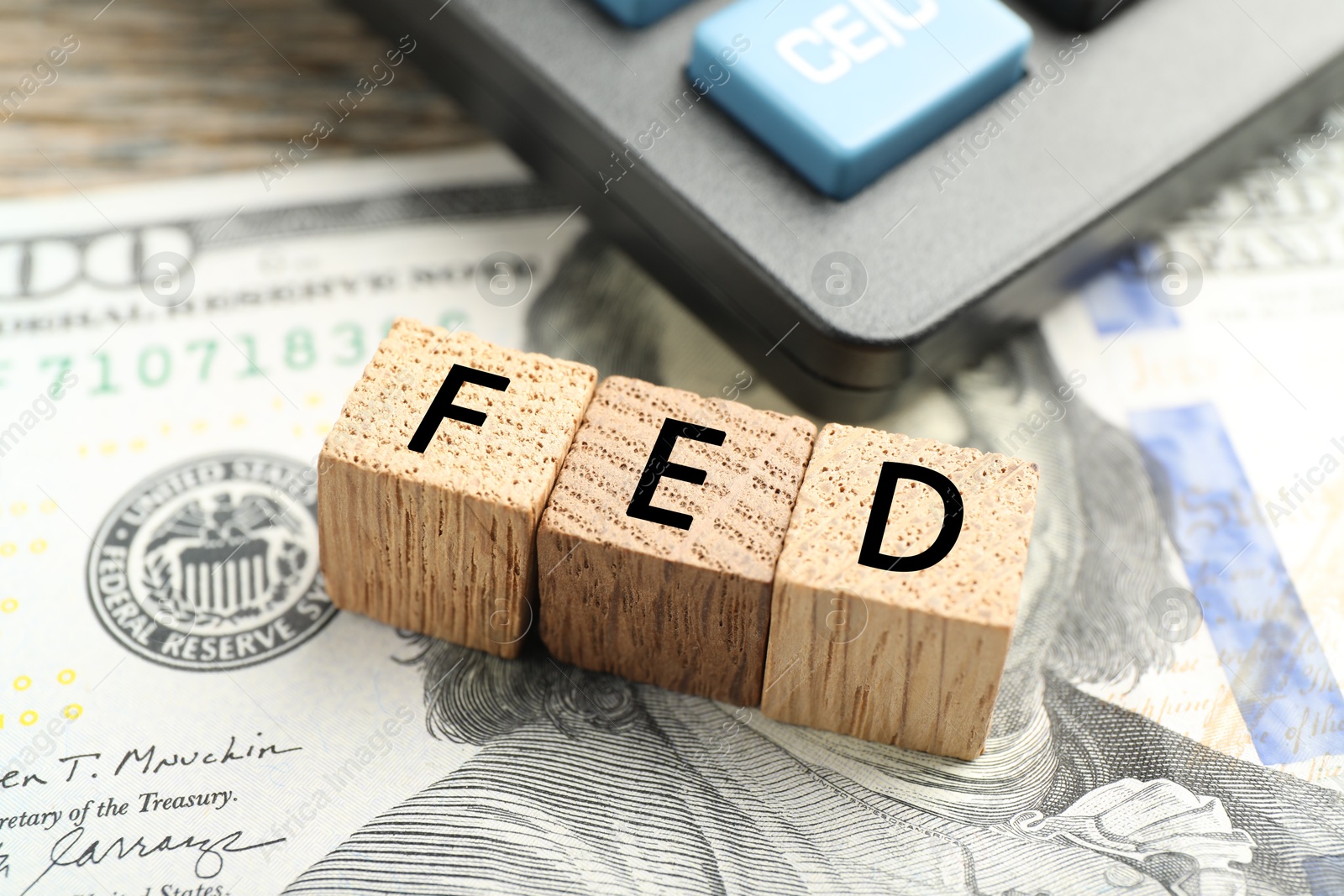 Photo of Wooden cubes with letters Fed (Federal Reserve System) and dollar banknote on table, closeup