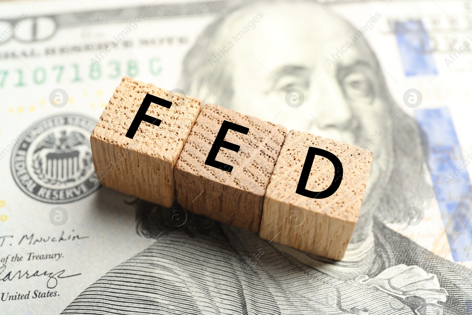 Photo of Wooden cubes with letters Fed (Federal Reserve System) on dollar banknote, closeup