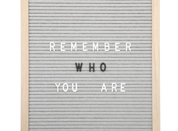 Photo of Letter board with phrase Remember who you are on white background, top view