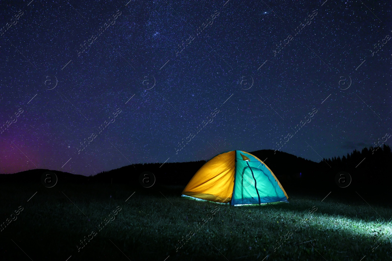 Photo of Modern camping tent in wilderness at night