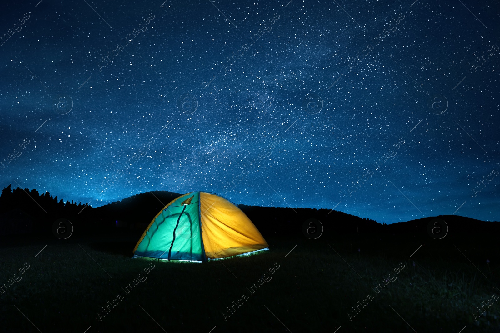 Photo of Modern camping tent in wilderness at night