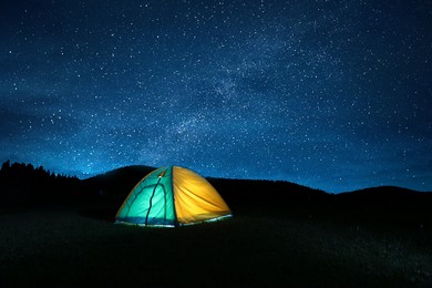 Photo of Modern camping tent in wilderness at night