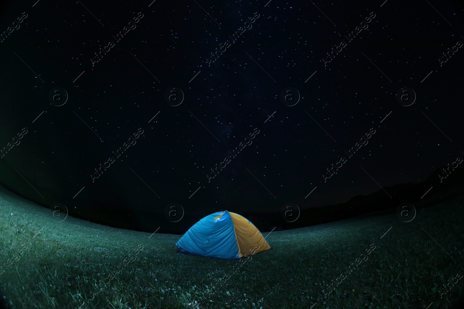 Photo of Modern camping tent in wilderness at night. Fisheye lens effect