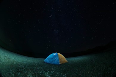 Photo of Modern camping tent in wilderness at night. Fisheye lens effect