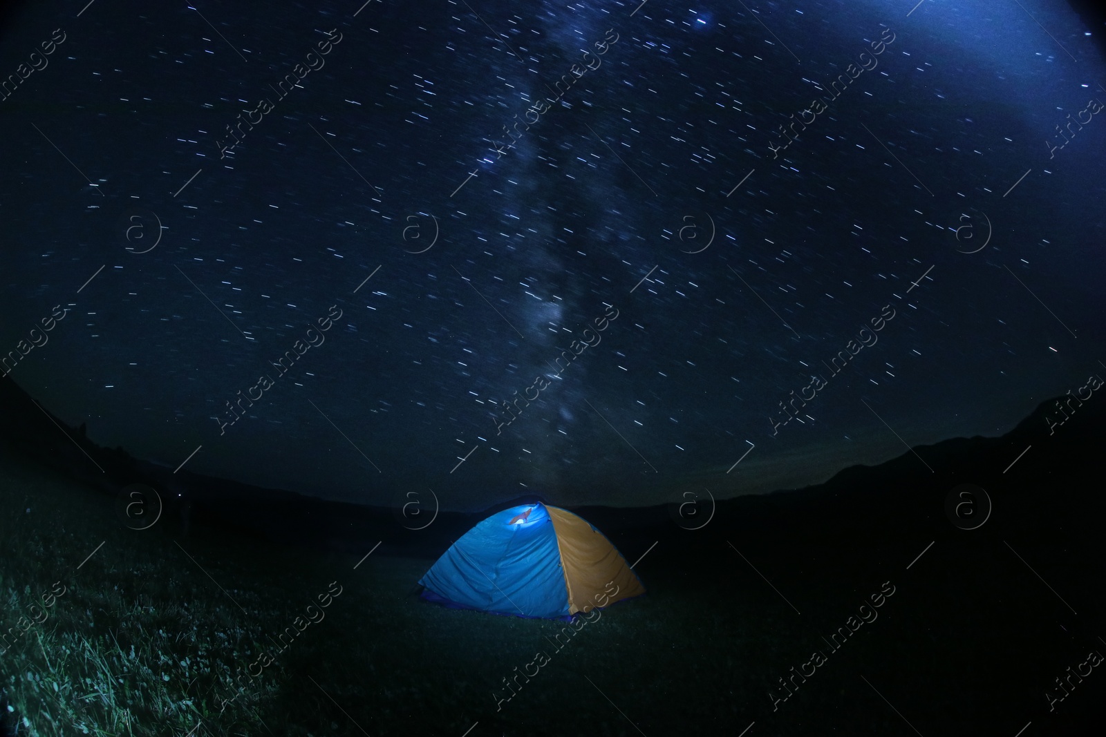 Photo of Modern camping tent in wilderness at night, slow shutter speed effect