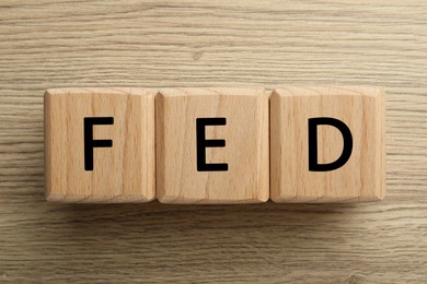 Photo of Cubes with letters Fed (Federal Reserve System) on wooden table, top view