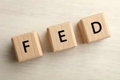 Photo of Cubes with letters Fed (Federal Reserve System) on wooden table, top view