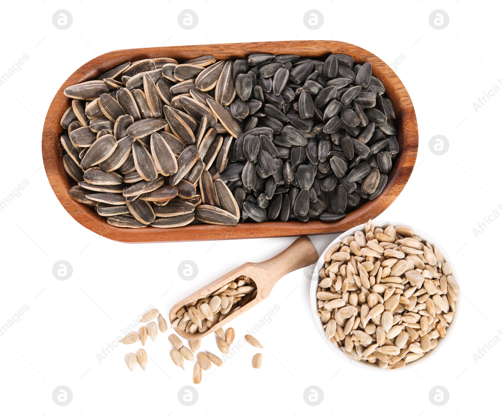 Photo of Different sunflower seeds, wooden plate, scoop and bowl isolated on white, top view