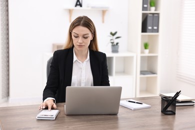 Photo of Banker with laptop and calculator working at wooden table in office