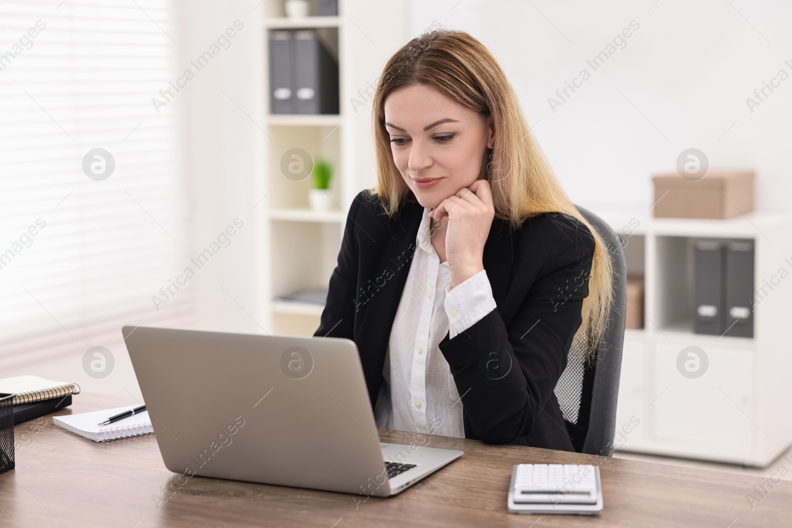 Photo of Banker using laptop at wooden table in office