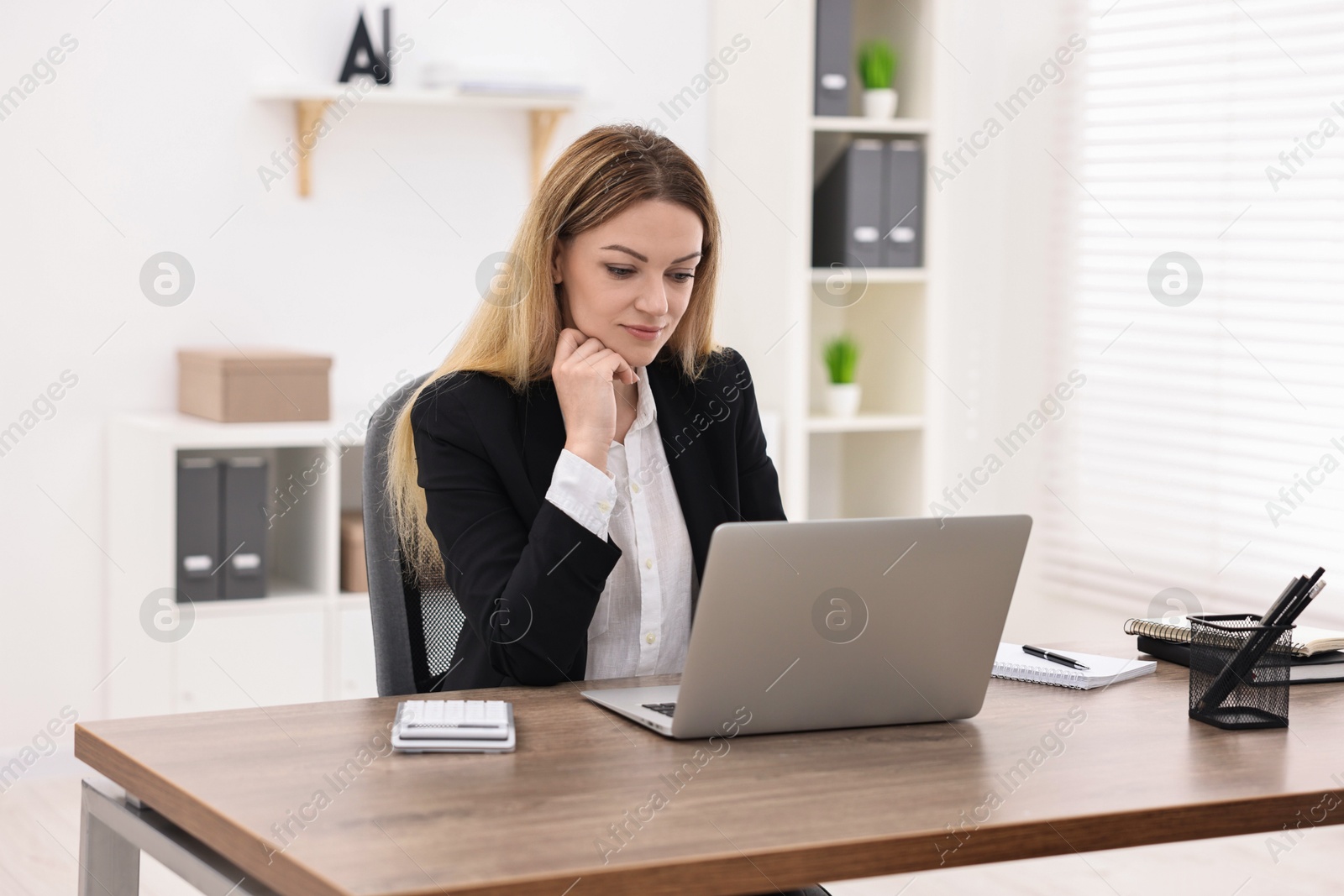 Photo of Banker using laptop at wooden table in office