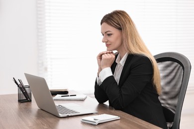 Photo of Banker with laptop working at wooden table in office