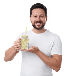 Photo of Happy man holding mason jar of water with lemon on white background