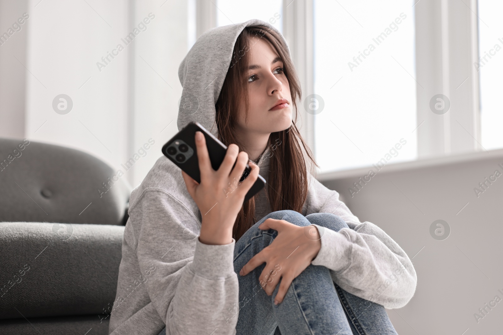 Photo of Loneliness concept. Sad teenage girl with smartphone listening to voice message at home