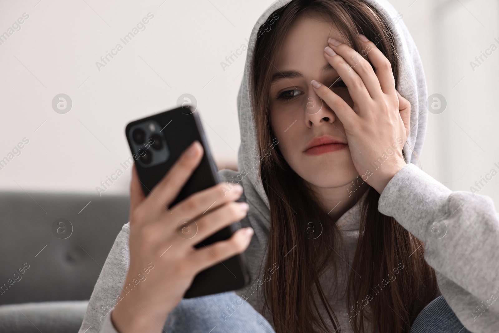 Photo of Loneliness concept. Sad teenage girl using smartphone at home