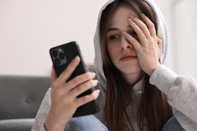 Loneliness concept. Sad teenage girl using smartphone at home