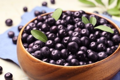 Photo of Ripe acai berries and leaves in bowl on grey table, closeup