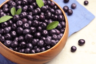 Photo of Ripe acai berries and leaves in bowl on grey table, closeup