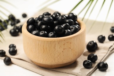 Photo of Ripe acai berries in bowl on light table, closeup