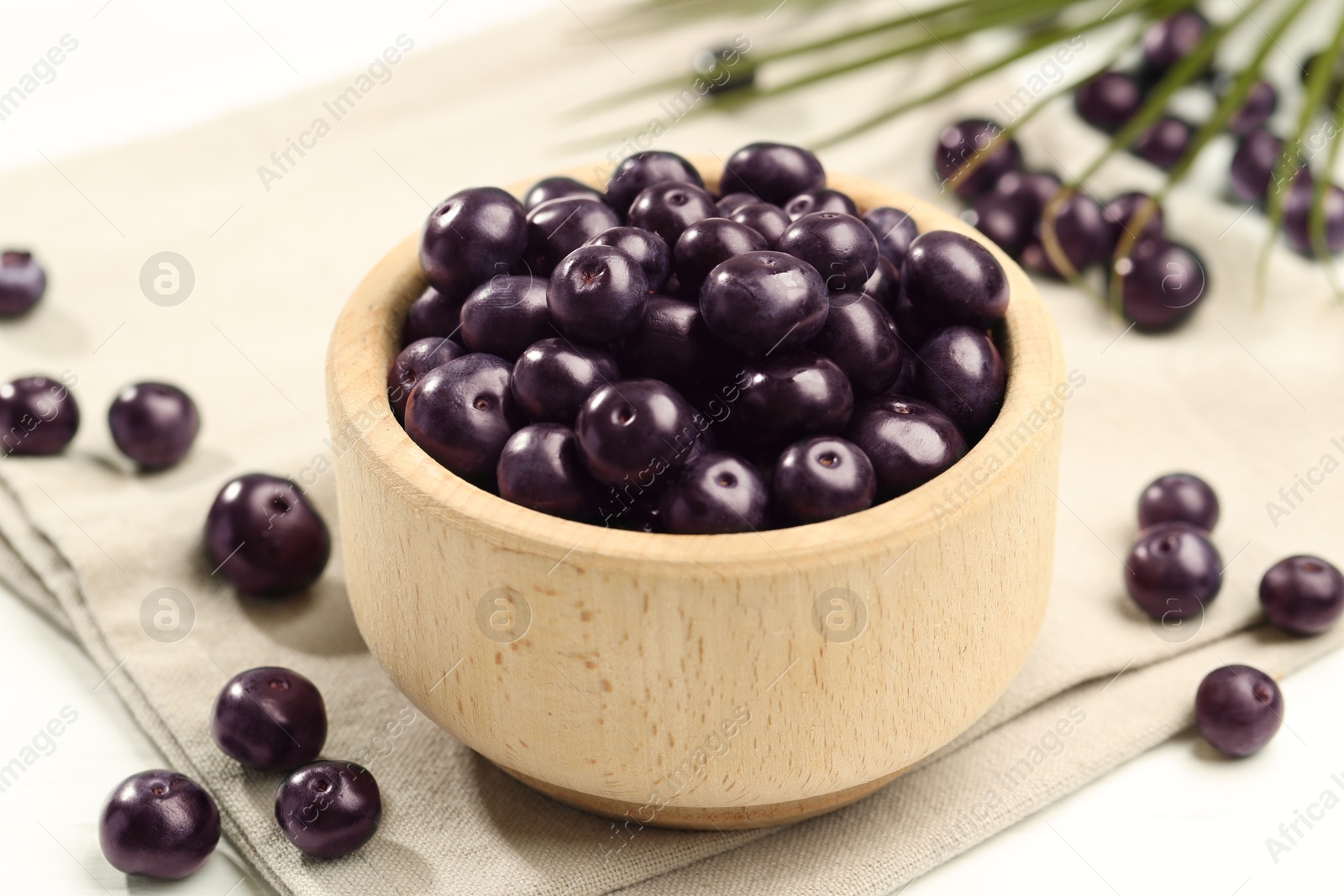 Photo of Ripe acai berries in bowl on light table, closeup