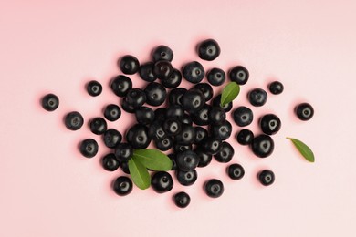 Photo of Ripe acai berries and leaves on pink background, flat lay