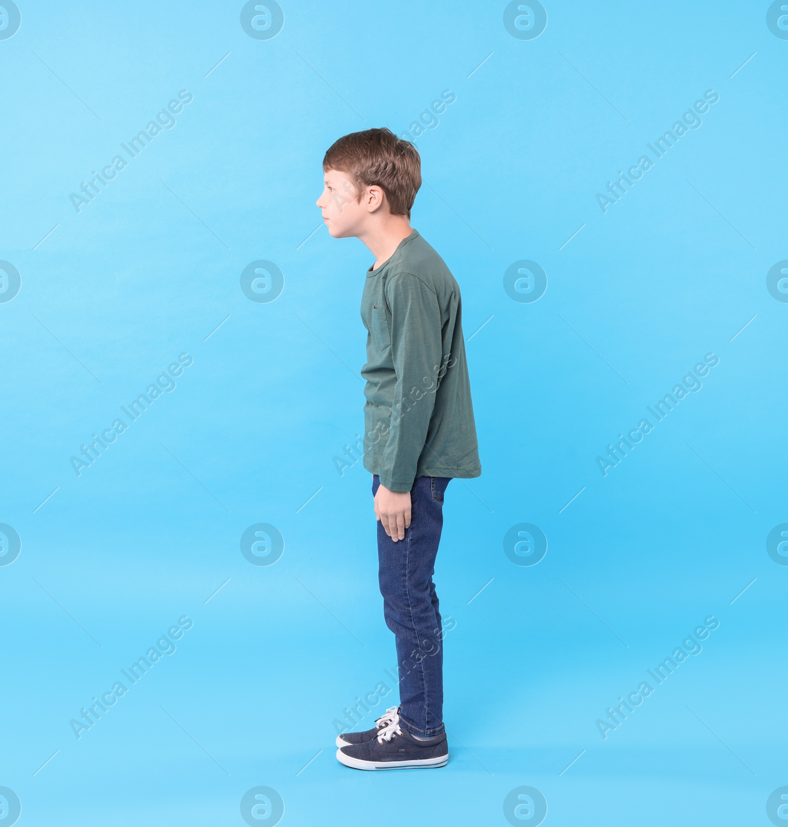 Photo of Boy with incorrect posture on light blue background