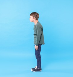 Boy with incorrect posture on light blue background