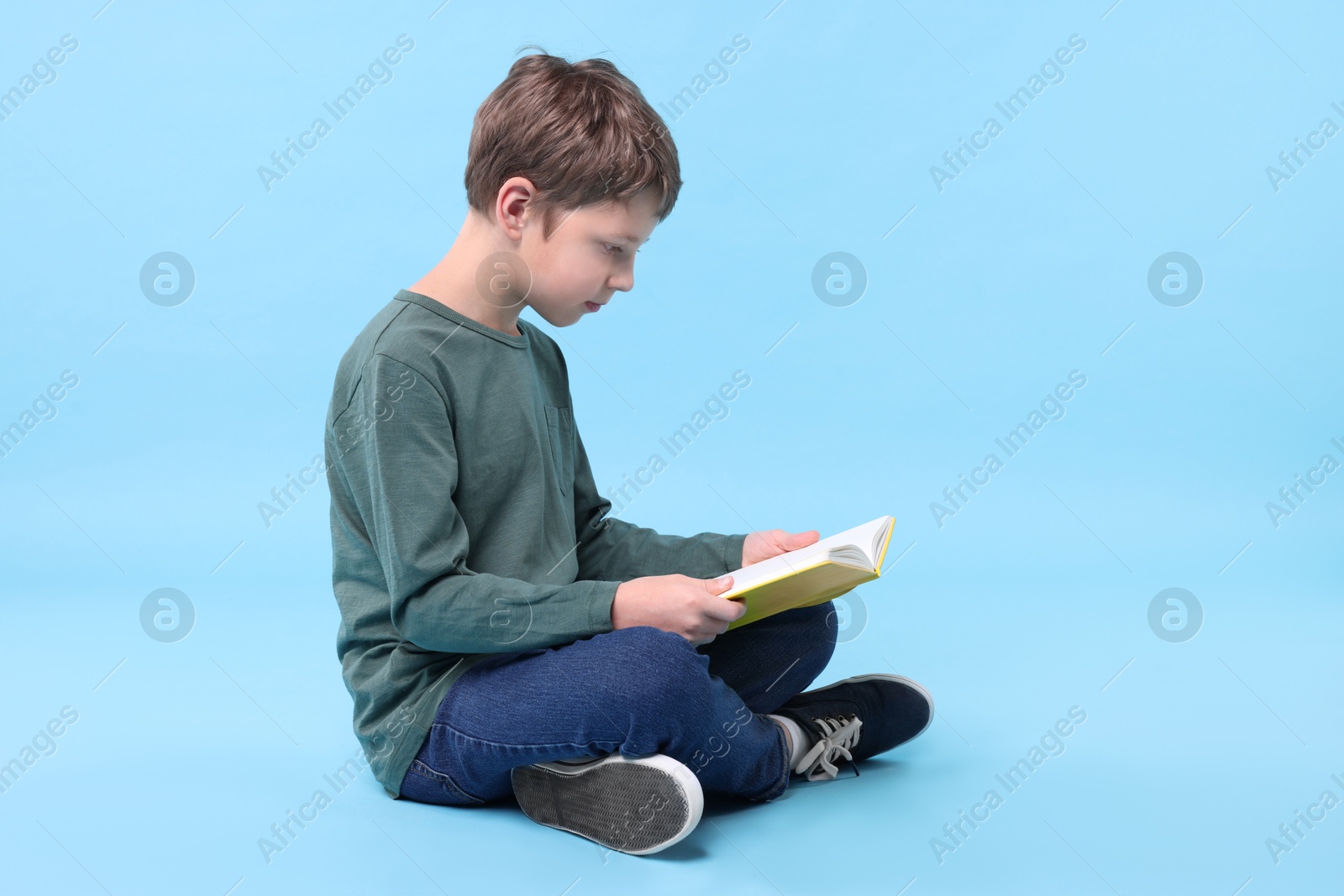 Photo of Boy with correct posture reading book on light blue background