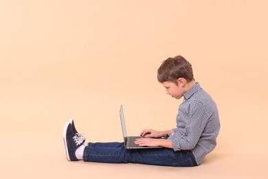 Photo of Boy with incorrect posture and laptop sitting on beige background