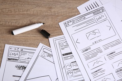 Photo of Developing UI design. Sketches of website wireframes and felt pen on wooden table, top view