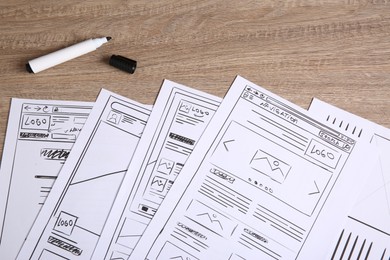 Photo of Developing UI design. Sketches of website wireframes and felt pen on wooden table, top view