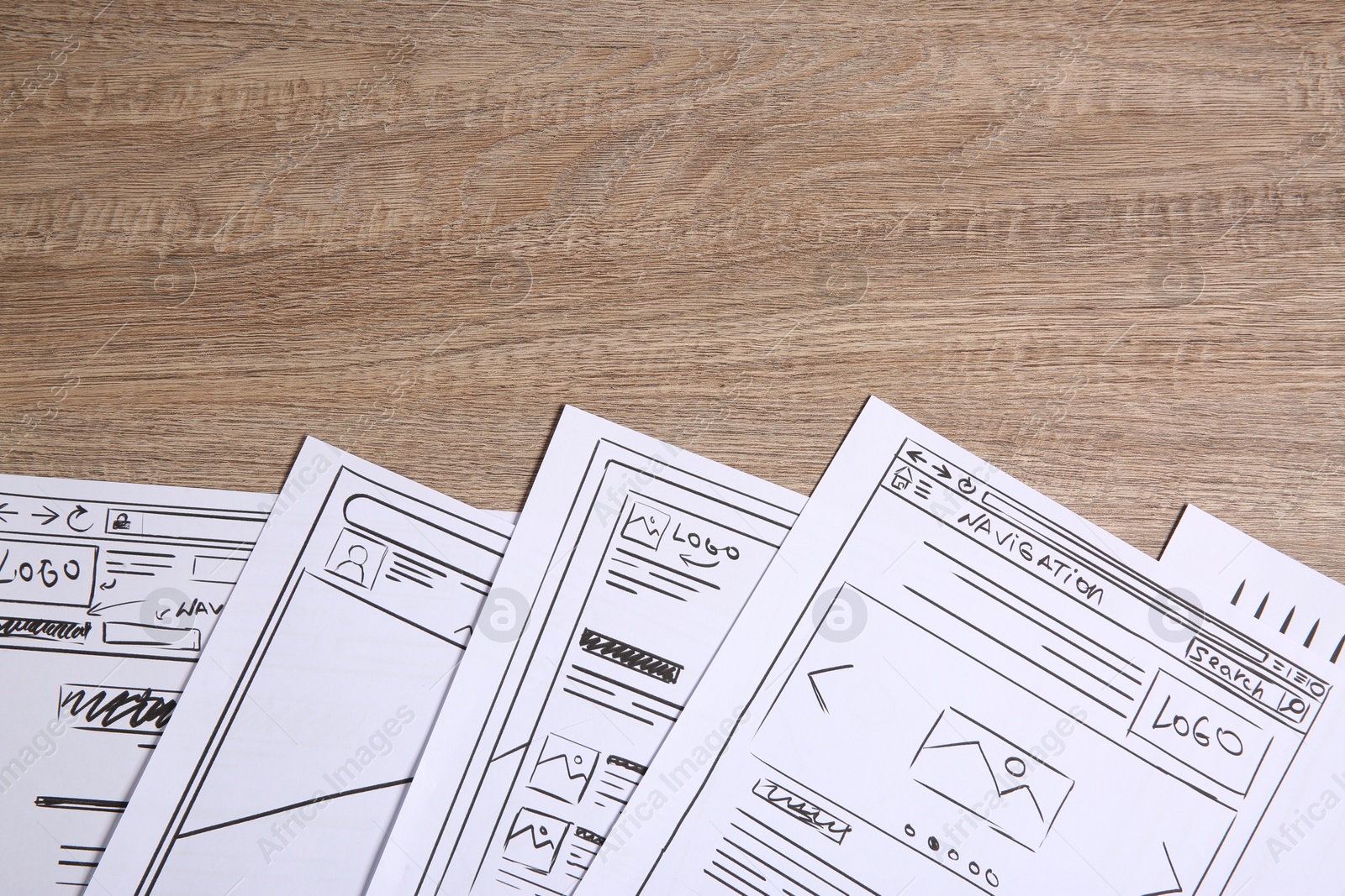 Photo of Developing UI design. Sketches of website wireframes on wooden table, top view