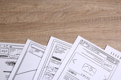 Photo of Developing UI design. Sketches of website wireframes on wooden table, top view