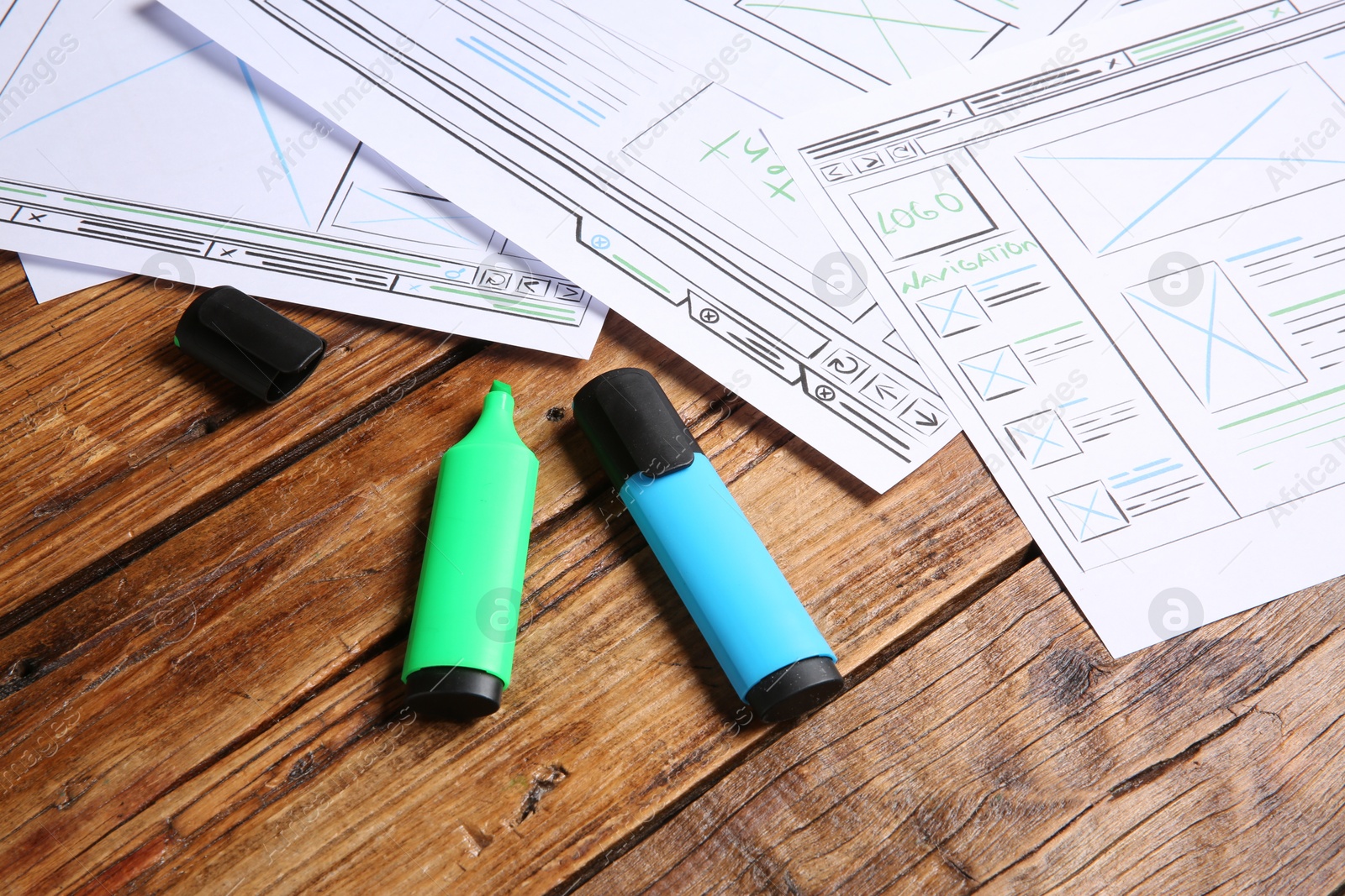 Photo of Developing UI design. Sketches of website wireframes and felt pens on wooden table, closeup