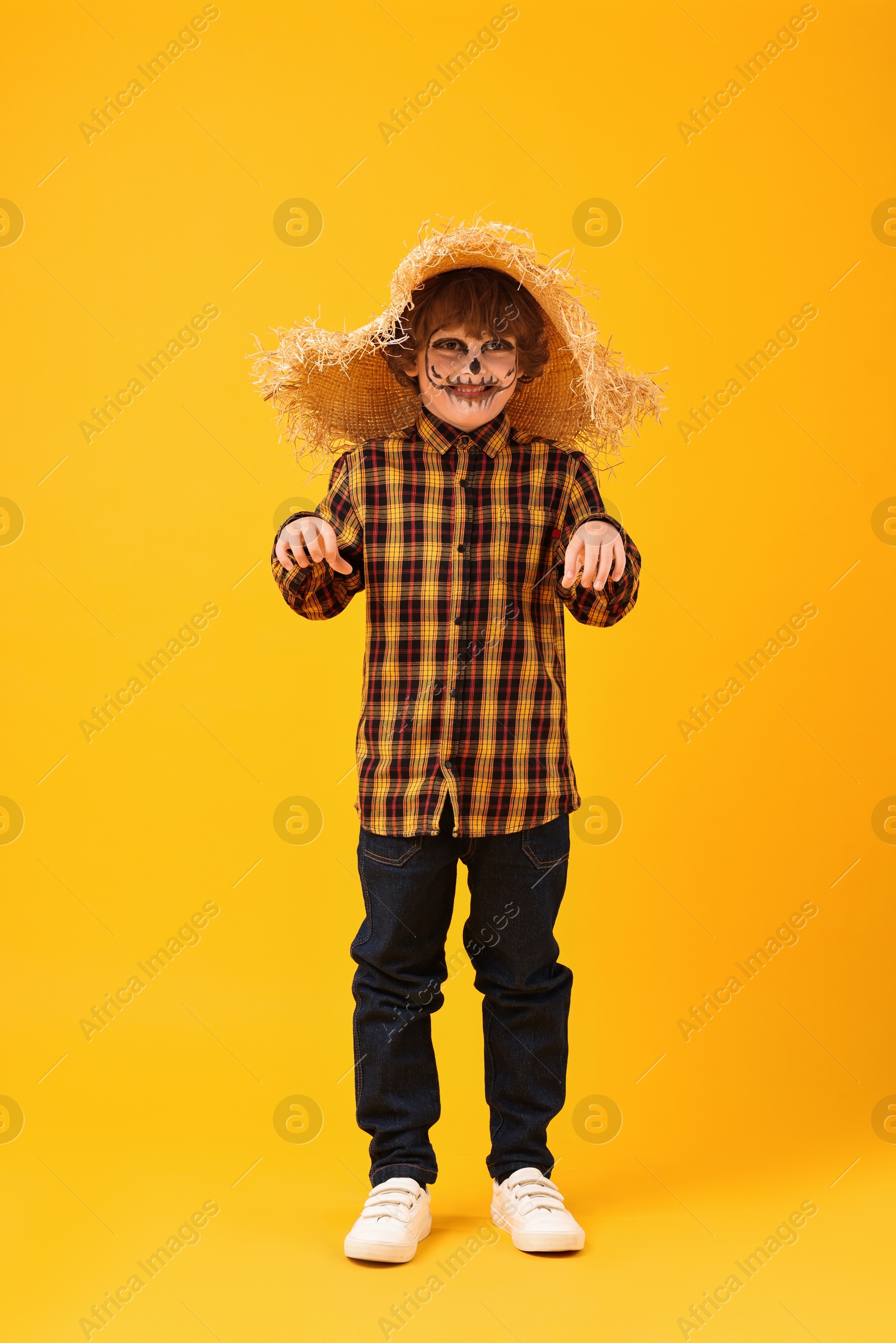 Photo of Funny boy dressed like scarecrow on yellow background. Halloween celebration