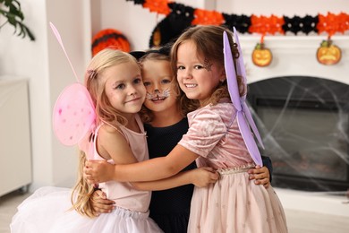 Photo of Cute girls wearing costumes for Halloween celebration in room