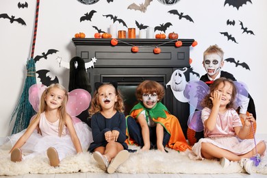 Funny children wearing costumes for Halloween celebration in decorated room