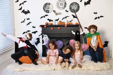 Funny children wearing costumes for Halloween celebration in decorated room