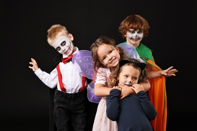 Photo of Funny children wearing costumes for Halloween celebration on black background