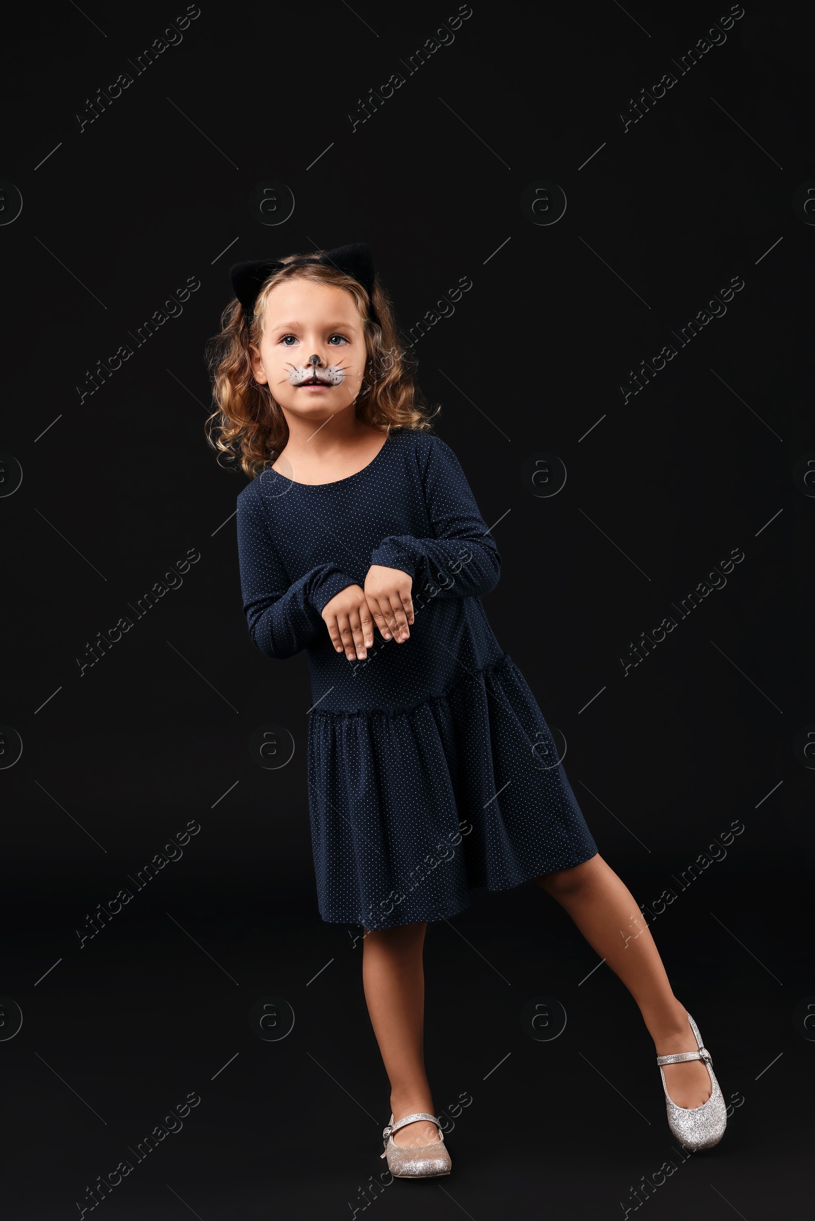 Photo of Funny girl dressed like cat for Halloween celebration on black background