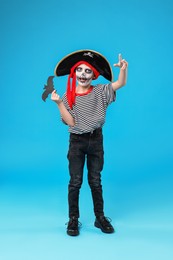 Funny boy with paper bat dressed like pirate on light blue background. Halloween costume