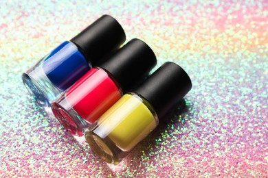 Nail polishes in bottles on bright textured surface, closeup